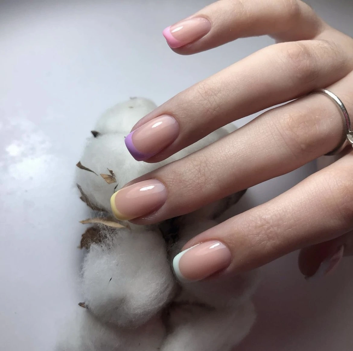 Nail technician in black holding pink gloves